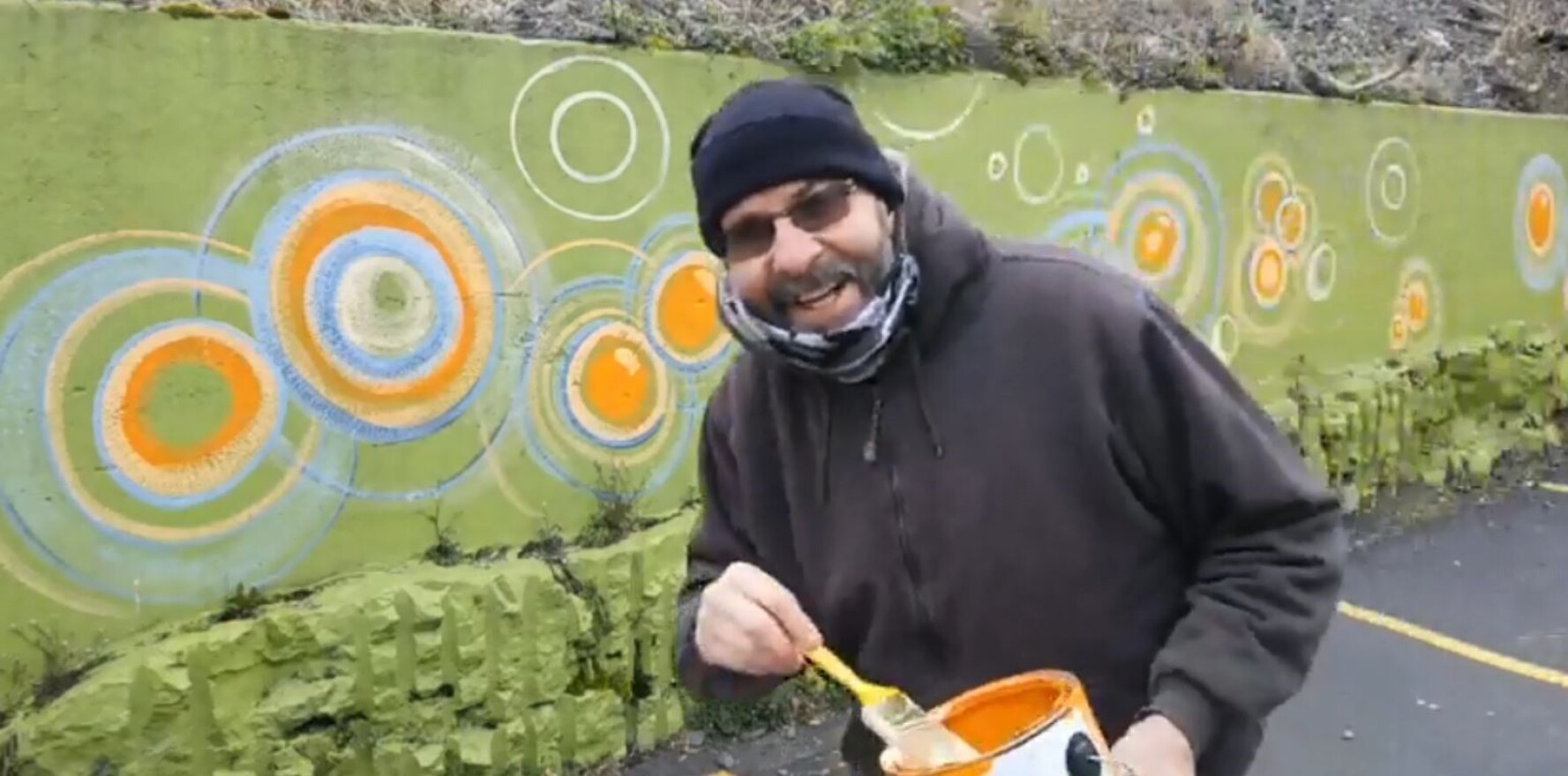 In a Facebook video, Rochester artist Mark Groaning paints a parking lot retaining wall at Artisan Works.
